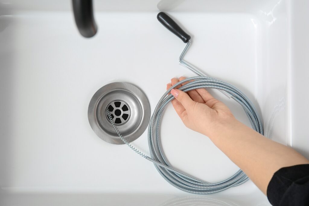 Plumber cleaning clogged residential drain